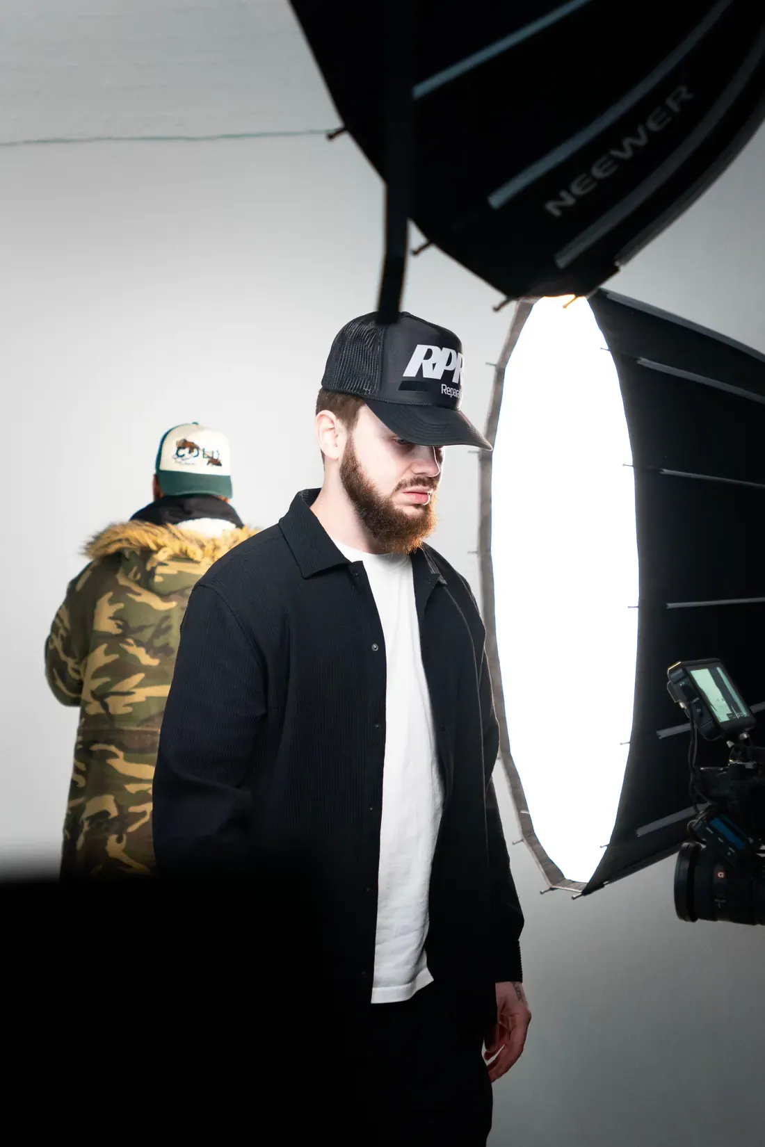 Laurence Ascott on set, stood beside a lit softbox with a camera rigged behind him