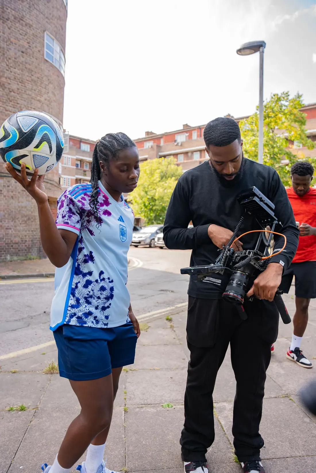 Filming a young footballer on a caged street court, the camera low as the player runs at the ball